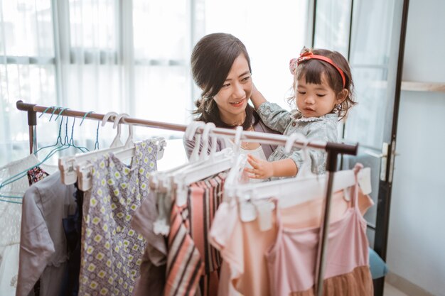 Aziatische moeder koopt kleding tijdens het winkelen met haar peuterbaby