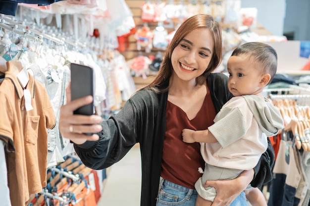 Aziatische moeder neemt selfie met haar zoon tijdens het winkelen in het winkelcentrum