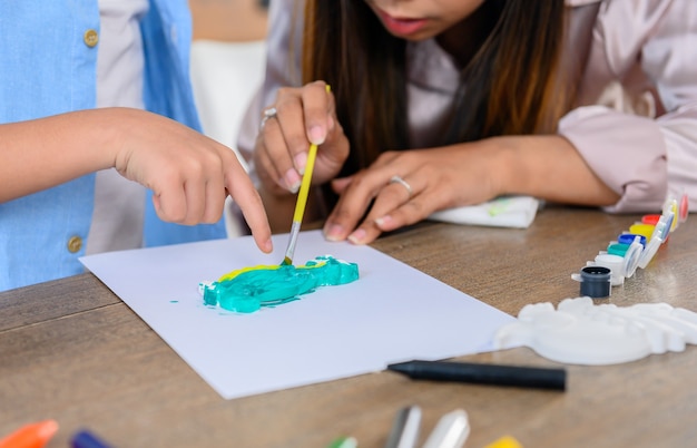 Aziatische moeder werkt thuis samen met zoon. moeder en kind tekenen foto en kleur schilderen kunst. vrouw levensstijl en gezinsactiviteit.