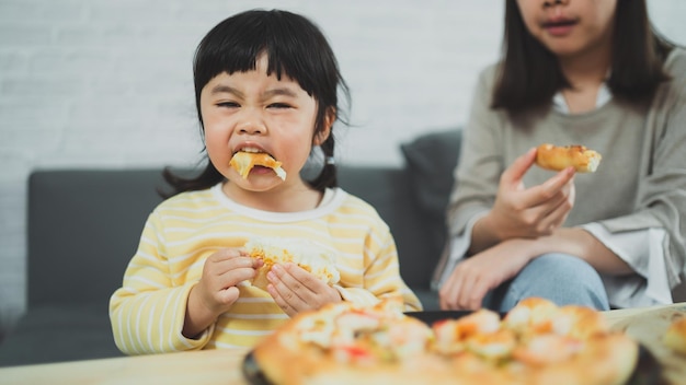 Aziatische moeders en kinderen doen thuis activiteiten Moeder gaat pizza eten voor haar kinderen Kinderen eten en proeven Italiaanse zelfgemaakte pizza