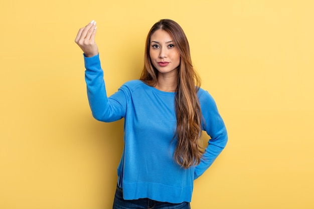 Aziatische mooie vrouw die capice of geldgebaar maakt en u vertelt om uw schulden te betalen!