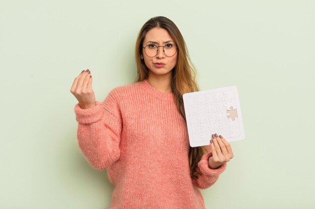 aziatische mooie vrouw die capice of geldgebaar maakt en u vertelt te betalen. puzzel concept