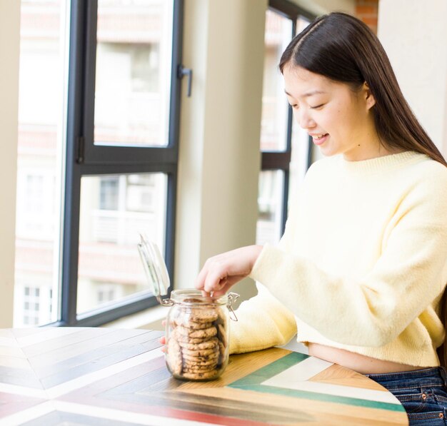 Aziatische mooie vrouw die koekjes eet bij koele woonkamer