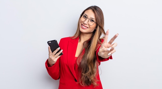 Aziatische mooie vrouw die lacht en er gelukkig uitziet, gebarend naar overwinning of vrede. bedrijfs- en telefoonconcept.