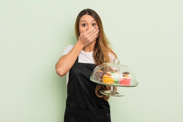 Aziatische mooie vrouw die mond bedekt met handen met een geschokt. zelfgemaakte taarten concept