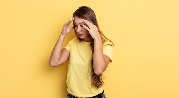 Aziatische mooie vrouw die ogen bedekt met handen met een droevige, gefrustreerde blik van wanhoop, huilend, zijaanzicht