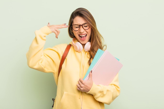 Aziatische mooie vrouw die ongelukkig en gestrest kijkt, zelfmoordgebaar dat pistoolteken maakt. universitair studentenconcept