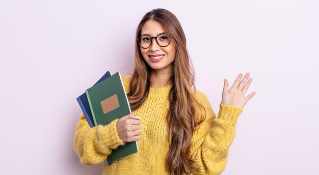 Aziatische mooie vrouw die vrolijk lacht, met de hand zwaait, je verwelkomt en begroet. studentenconcept