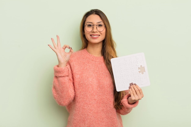 Aziatische mooie vrouw die zich gelukkig voelt, goedkeuring toont met een goed gebaar. puzzel concept