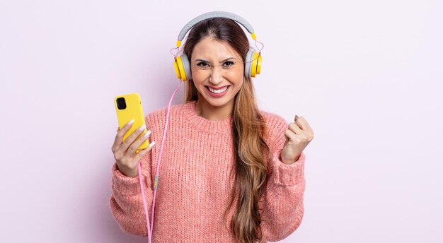 Aziatische mooie vrouw die zich geschokt voelt, lacht en succes viert. koptelefoon en telefoon concept