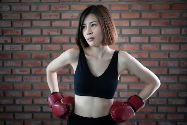 Aziatische mooie vrouw draagt bokshandschoenen in de sportschool