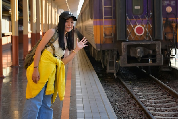 Aziatische mooie vrouw met een rugpeddelrugzak Lopend om een trein te nemen op het perron