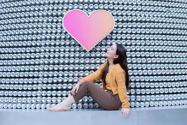 Aziatische mooie vrouw met lang haar draagt een gele trui en lacht vrolijk in Valentijnsthema