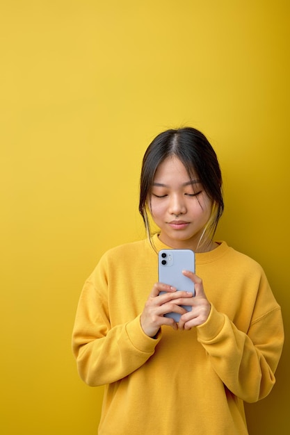 Aziatische mooie vrouw permanent in geel shirt met mobiele telefoon in handen bereid je voor om te bellen mensen en technologie concept chinese dame chatten online browsen op sociale media