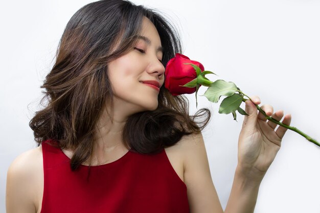Aziatische mooie vrouwen ruiken rode roos en glimlachen van geluk valentijnsdag en liefde