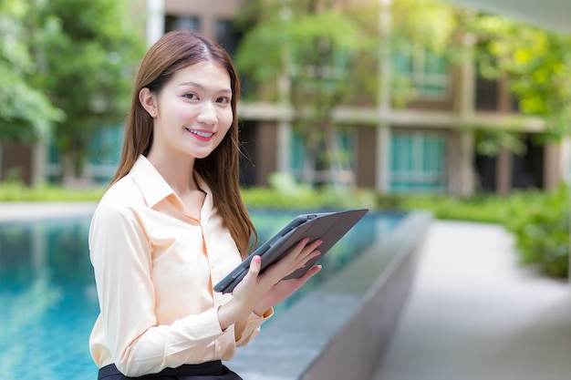 Aziatische mooie werkende vrouw gebruikt tablet om gegevens te zoeken bij het werken vanaf elke plek concept