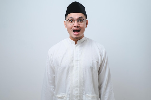Aziatische moslim man geschokt gebaar kan niet geloven wat hij ziet bezorgde uitdrukking tegen witte achtergrond