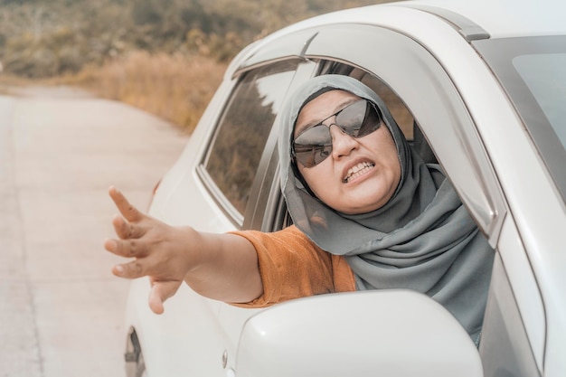 Aziatische moslim vrouwelijke chauffeur wordt boos boos van het verkeer schreeuwt en toont onbeleefde gebaren