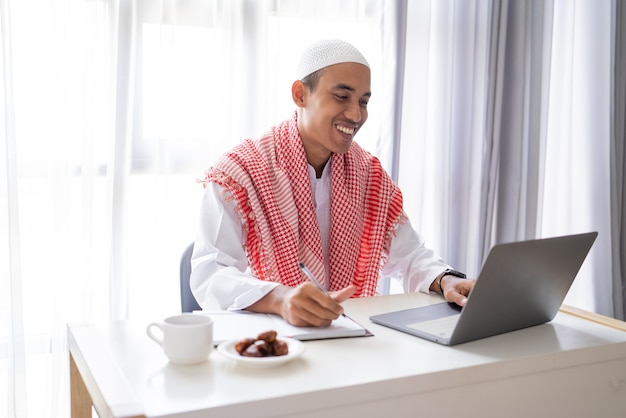 Aziatische moslim zakenman werken met behulp van laptop zittend op het bureau