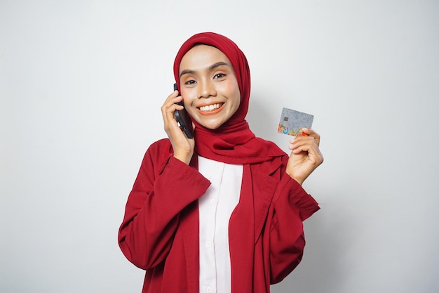 Aziatische moslim zakenvrouw in rood casual met een smartphone en een creditcard