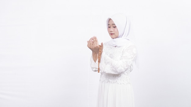 Aziatische moslimvrouw die gebedparels draagt bidt in wit