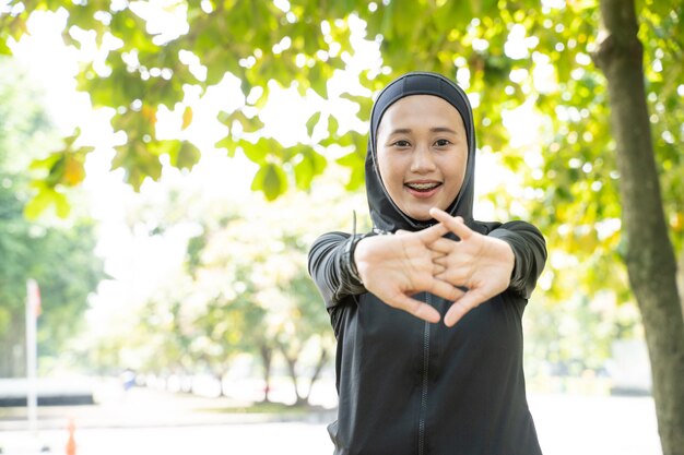 Aziatische moslimvrouw die haar arm uitrekt tijdens het sporten buiten