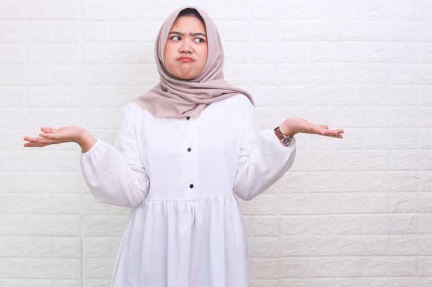 Aziatische moslimvrouw die moslim hijab draagt, geen idee en verwarde uitdrukking met opgeheven armen en handen