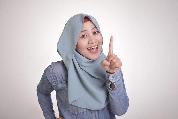 Aziatische moslimvrouw glimlachend en opsteken wijzende vinger nummer één