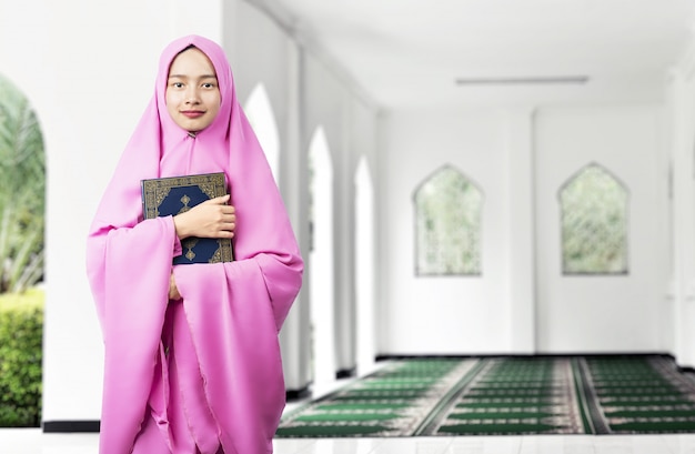 Aziatische Moslimvrouw in een sluier die en de Koran houdt houdt