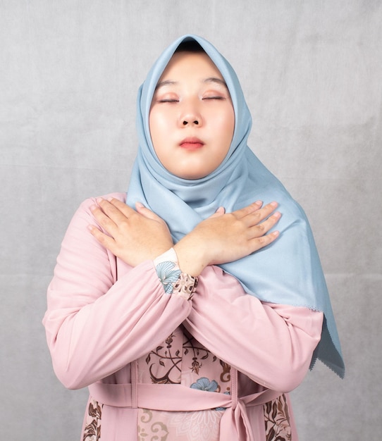 Aziatische moslimvrouwen met roze overhemden en blauwe hoofddoeken kruisen hun armen voor hun borst