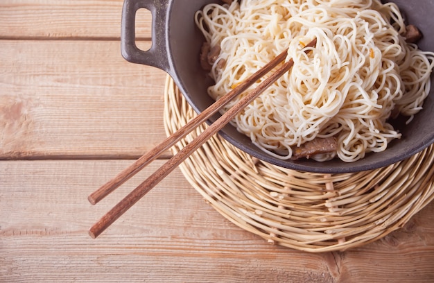 Aziatische noedels met rundvlees, groenten in de wok met stokjes