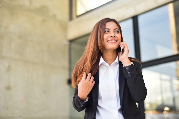 Aziatische onderneemster die smartphone smie gezicht gebruiken