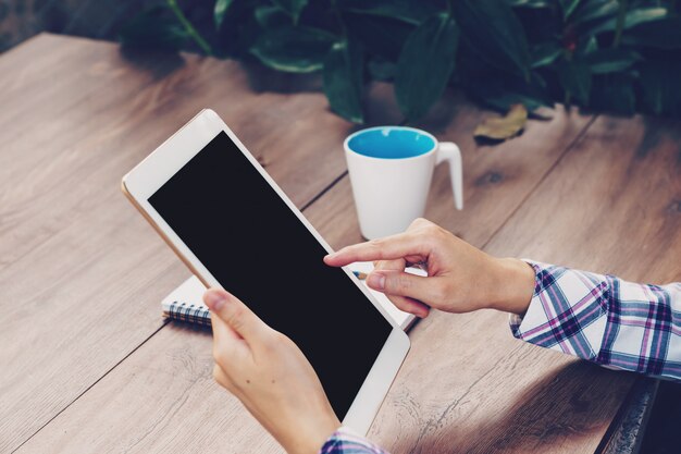 Aziatische onderneemster in de koffie en het gebruiken van tablet op lijst.