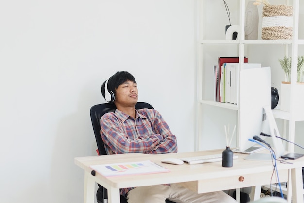 aziatische ondernemer rust terwijl hij tijdens het werken naar muziek luistert met een koptelefoon