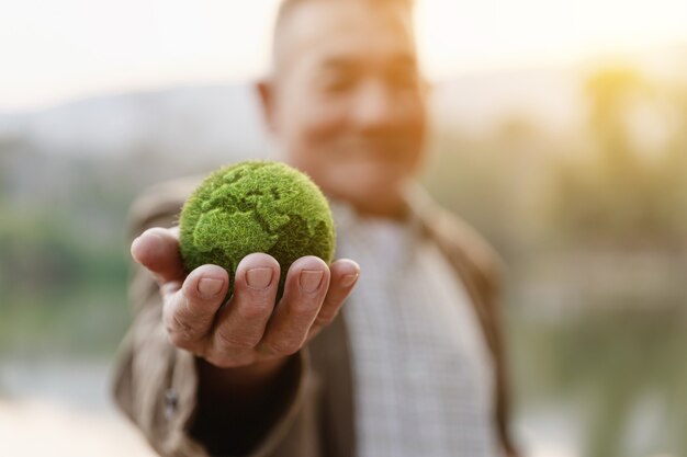 Aziatische oude man met aarde bij de hand, ecologie en milieu duurzaam concept.