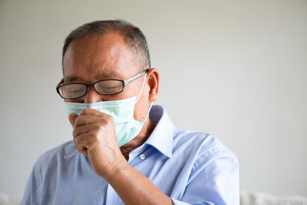 Aziatische oude man met beschermende gezichtsmasker en hoest