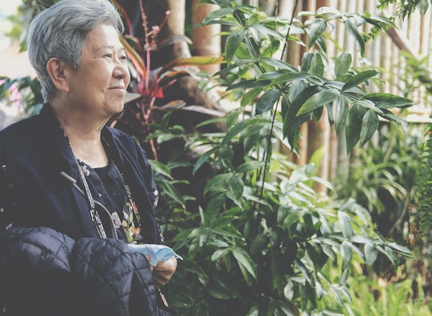 Aziatische oude oudere vrouwelijke oudere vrouw rust ontspannen in de tuin. senior vrije levensstijl