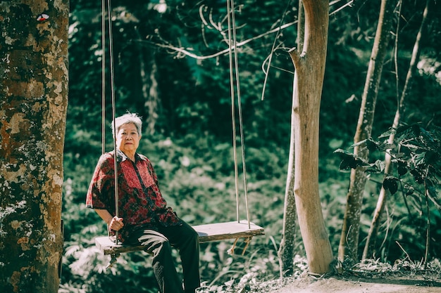 Aziatische oude oudere vrouwelijke oudere vrouw rust ontspannen op de schommel in de tuin. senior vrijetijds levensstijl