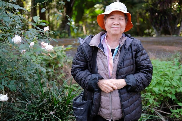 Aziatische oude oudere vrouwelijke oudere vrouw rusten ontspannen in bloementuin. senior vrije levensstijl