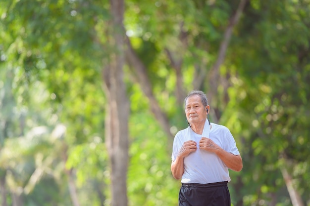 Aziatische oudere man of senior loper glimlach gelukkig in joggen outdoor en wandelen trainingen in het park.