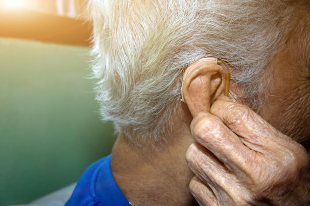 Aziatische oudere of oudere vrouw die een gehoorapparaat draagtclose-up hand van oudere vrouwen die een gehoorapparaat dragen