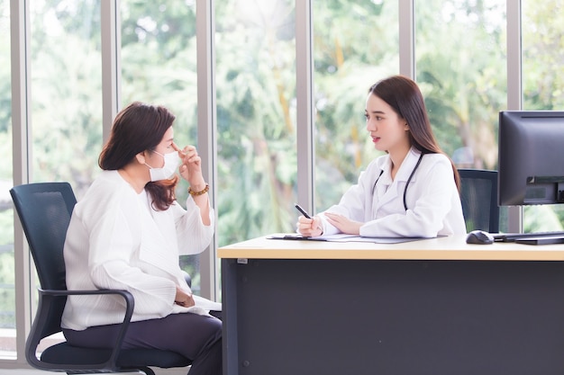 Aziatische oudere vrouw overlegt met arts over haar symptoom of gezondheidsprobleem in onderzoekskamer