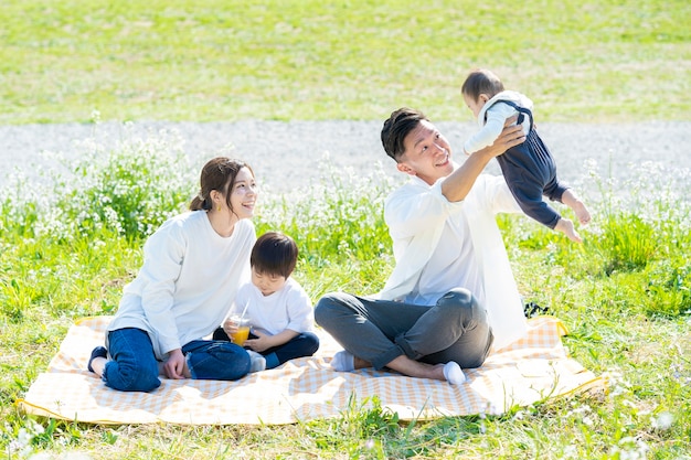 Aziatische ouders en kinderen die van een picknick op groen gebied genieten