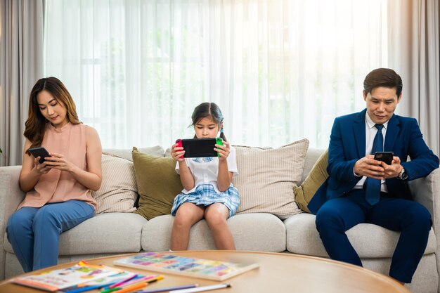 Aziatische ouders negeren hun kind en kijken thuis naar hun mobiele telefoon