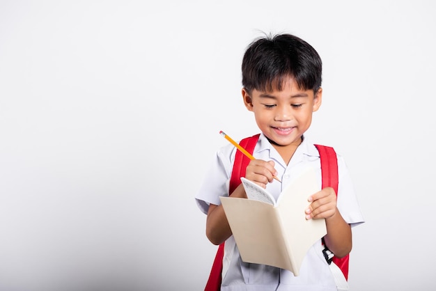 Aziatische peuter glimlachend gelukkig dragen student thai uniform rode broek met potlood voor schrijvers notebook