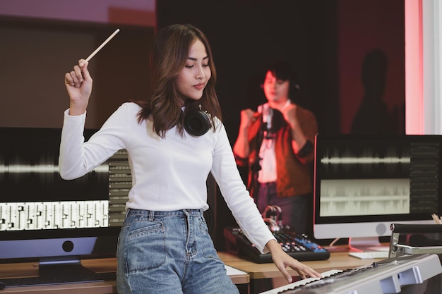 Aziatische producervrouw in wit overhemd bij de geluidsmengtafel