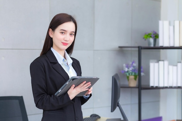 Aziatische professionele zakenvrouw in een zwart pak lacht vrolijk en kijkt naar de camera