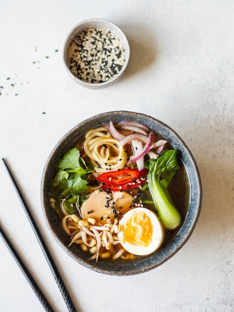 Aziatische Ramen-noedels met kip, pak choikool en ei op grijze achtergrond.