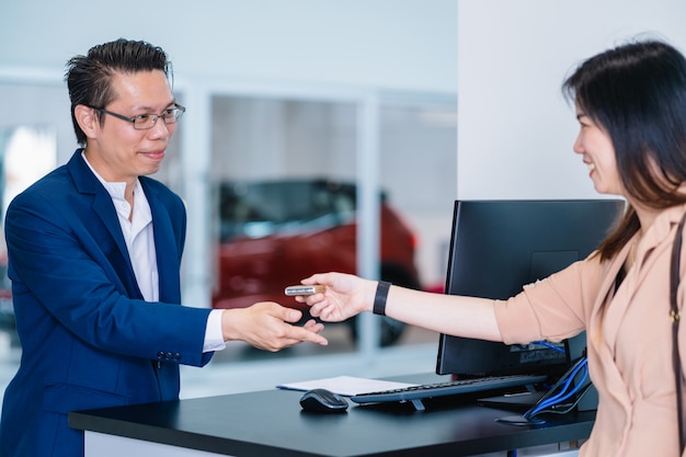 Aziatische receptioniste die de automatische autosleutel ontvangt voor het controleren bij onderhoudservicecentrum