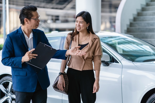 Aziatische receptionnist die de klant welkom heten om onderhoudservicecentrum te bezoeken om de auto te controleren